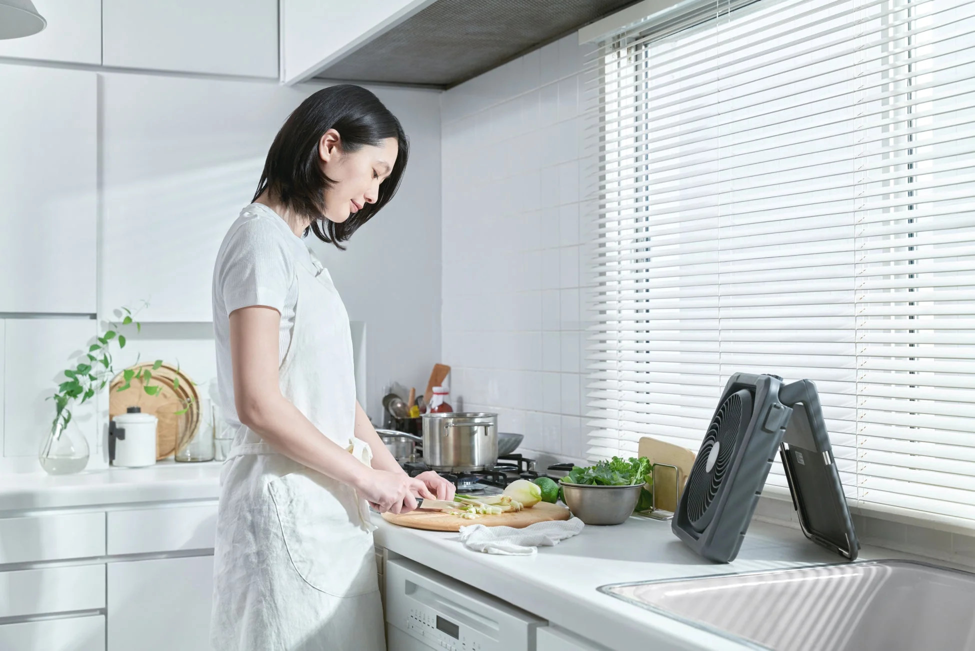 キッチンで女性が扇風機を使っている画像