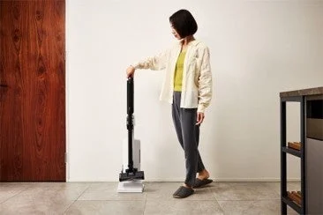 自動ゴミ収集ドックに掃除機を立てかける女性