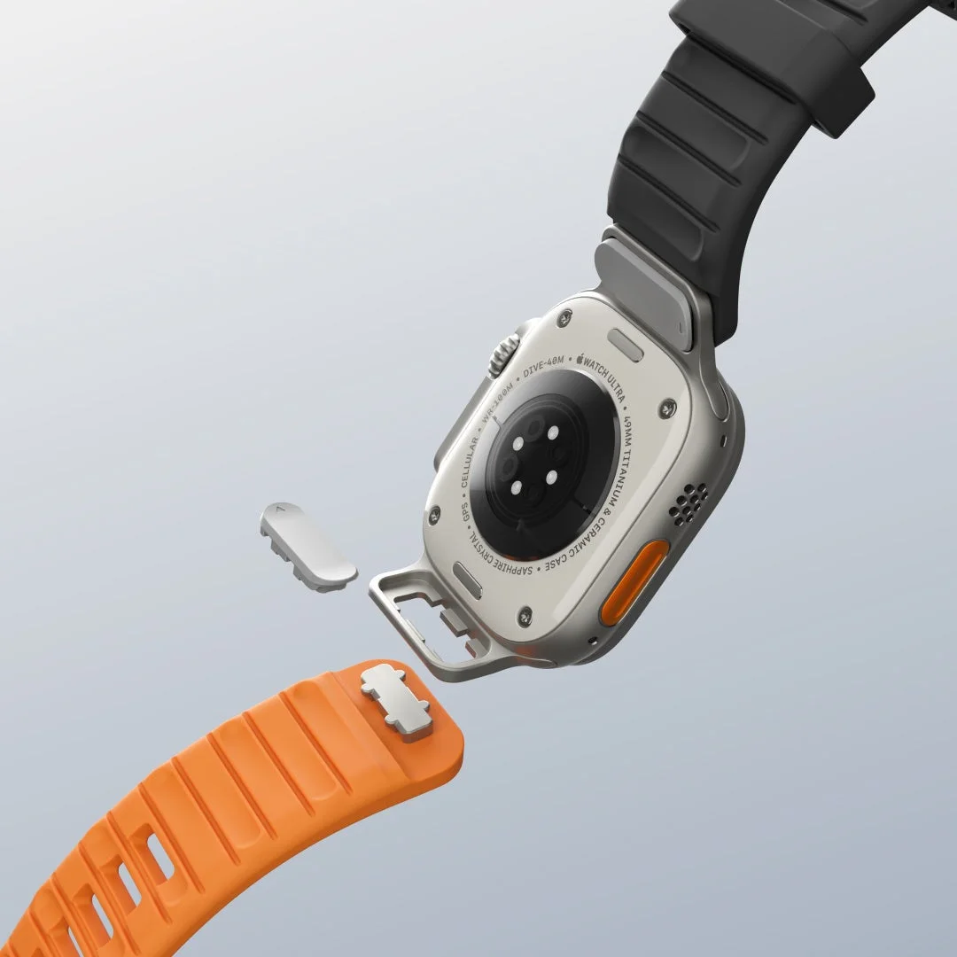 Apple Watch Ultraの背面がクローズアップされ、オレンジ色のバンドが取り付けまたは取り外しされている瞬間