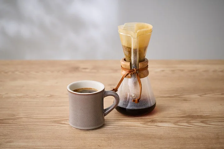 木製のテーブルに置かれたマグカップに入った淹れたてのコーヒー